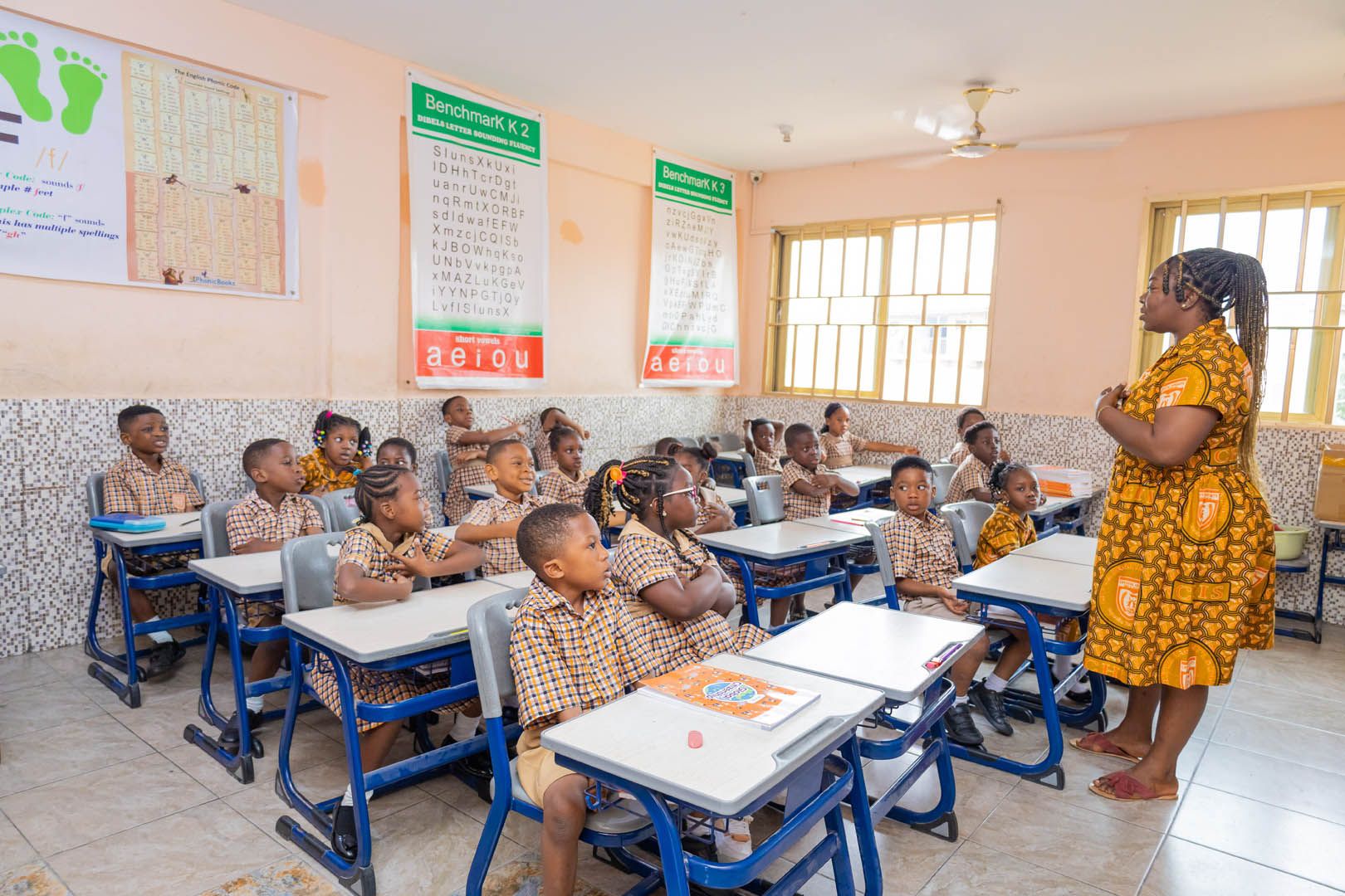 A Crystal Heights teacher with a full classroom of pupils in the school's checked uniform