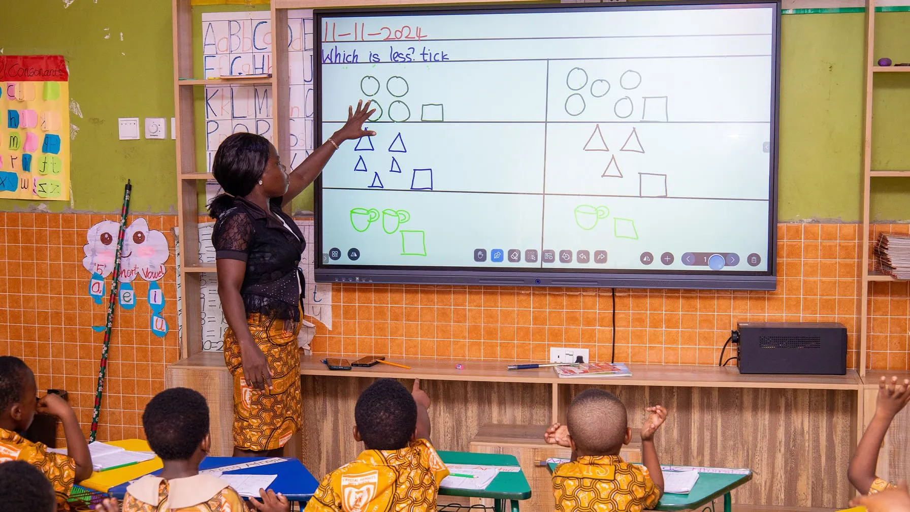 A Crystal Heights teacher at the interactive smart screen with a preschool class