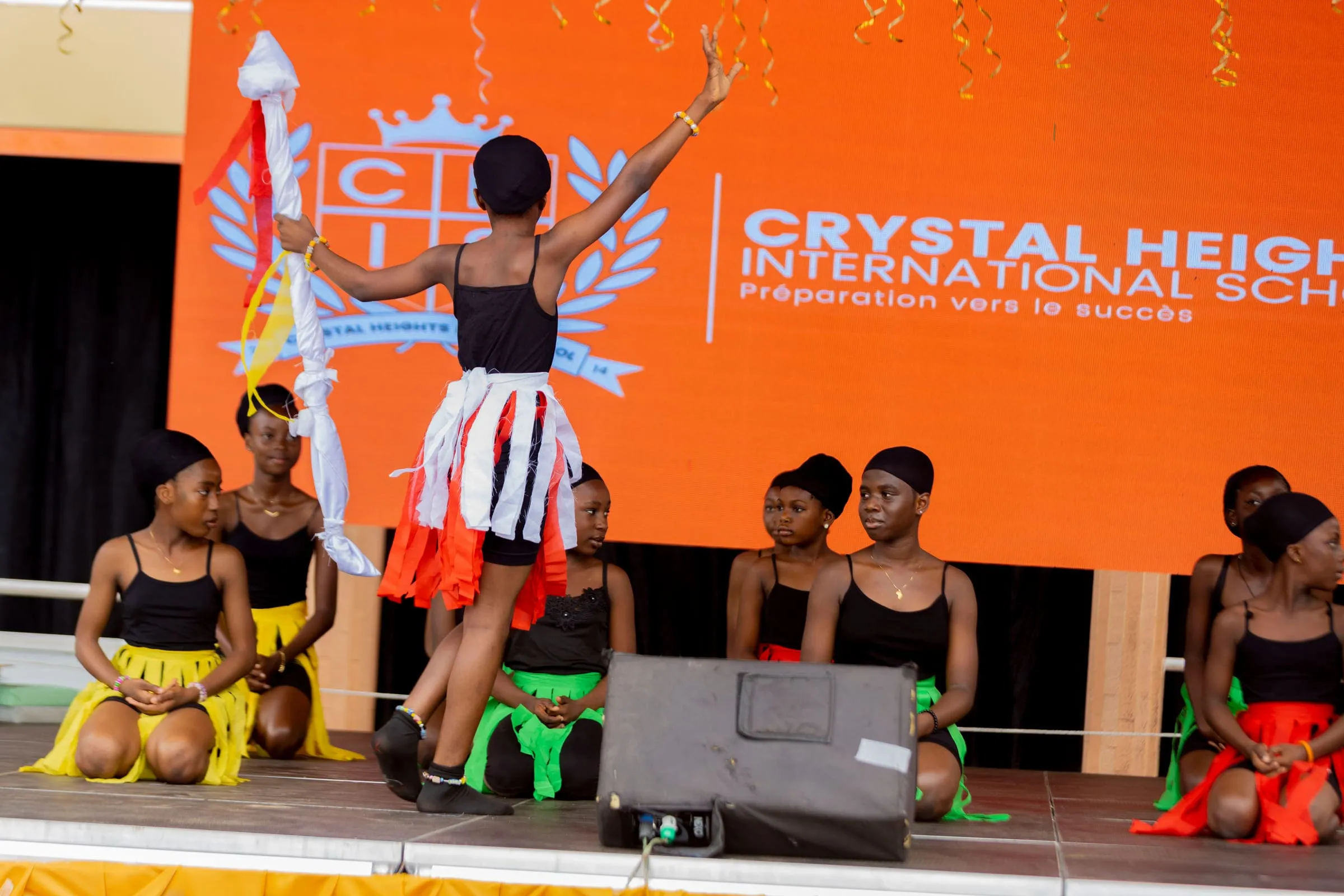 A pupil performing on stage in front of the Crystal Heights crest at Speech and Prize Giving
