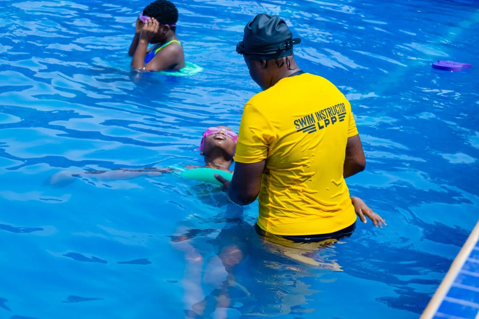 A swim instructor supporting a pupil floating on her back during a lesson