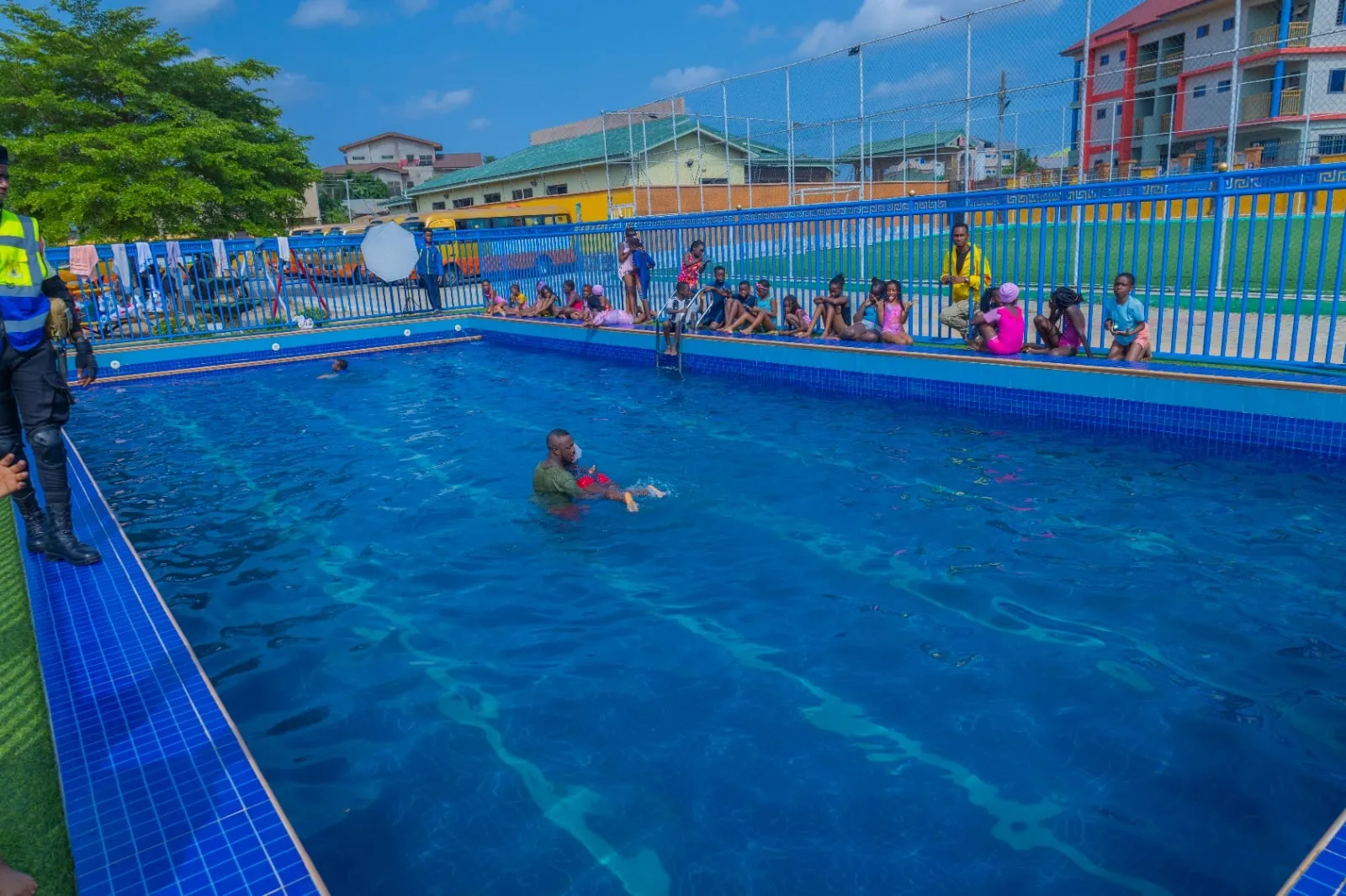 A swimming lesson in the pool at Crystal Heights, pupils waiting their turn at the poolside